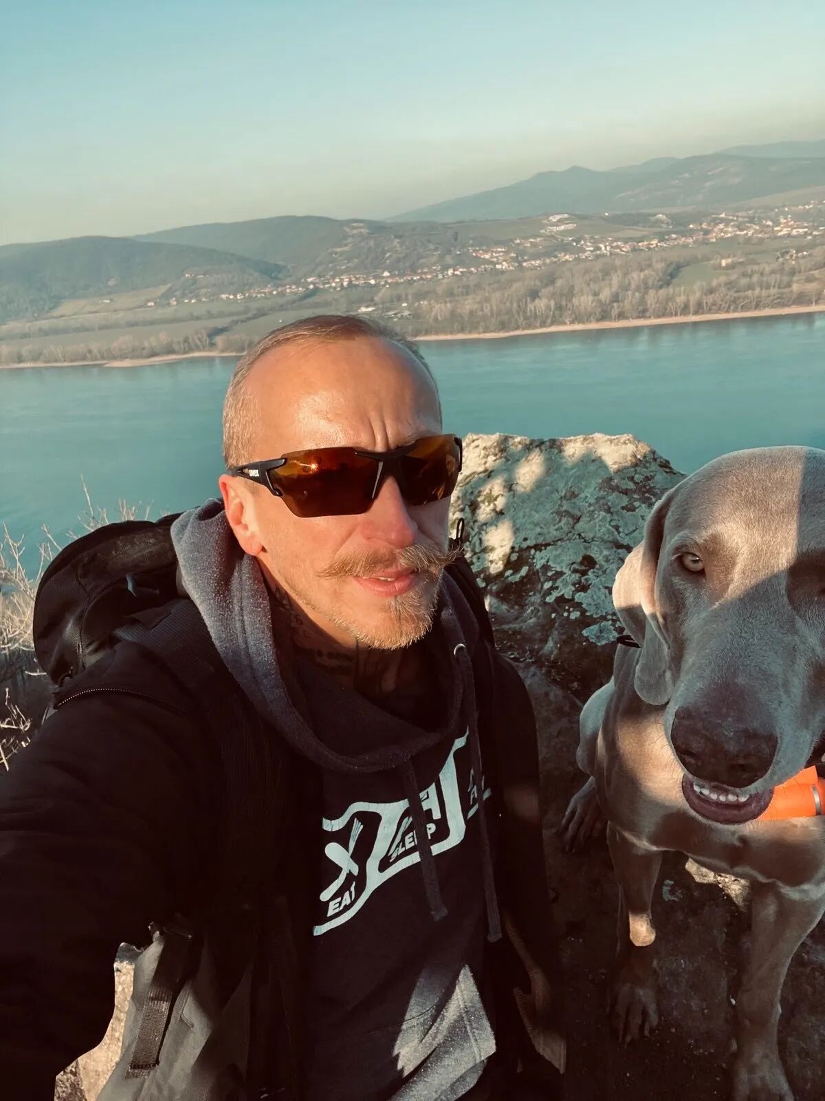 Guy in sunglasses with a vizsla near a river