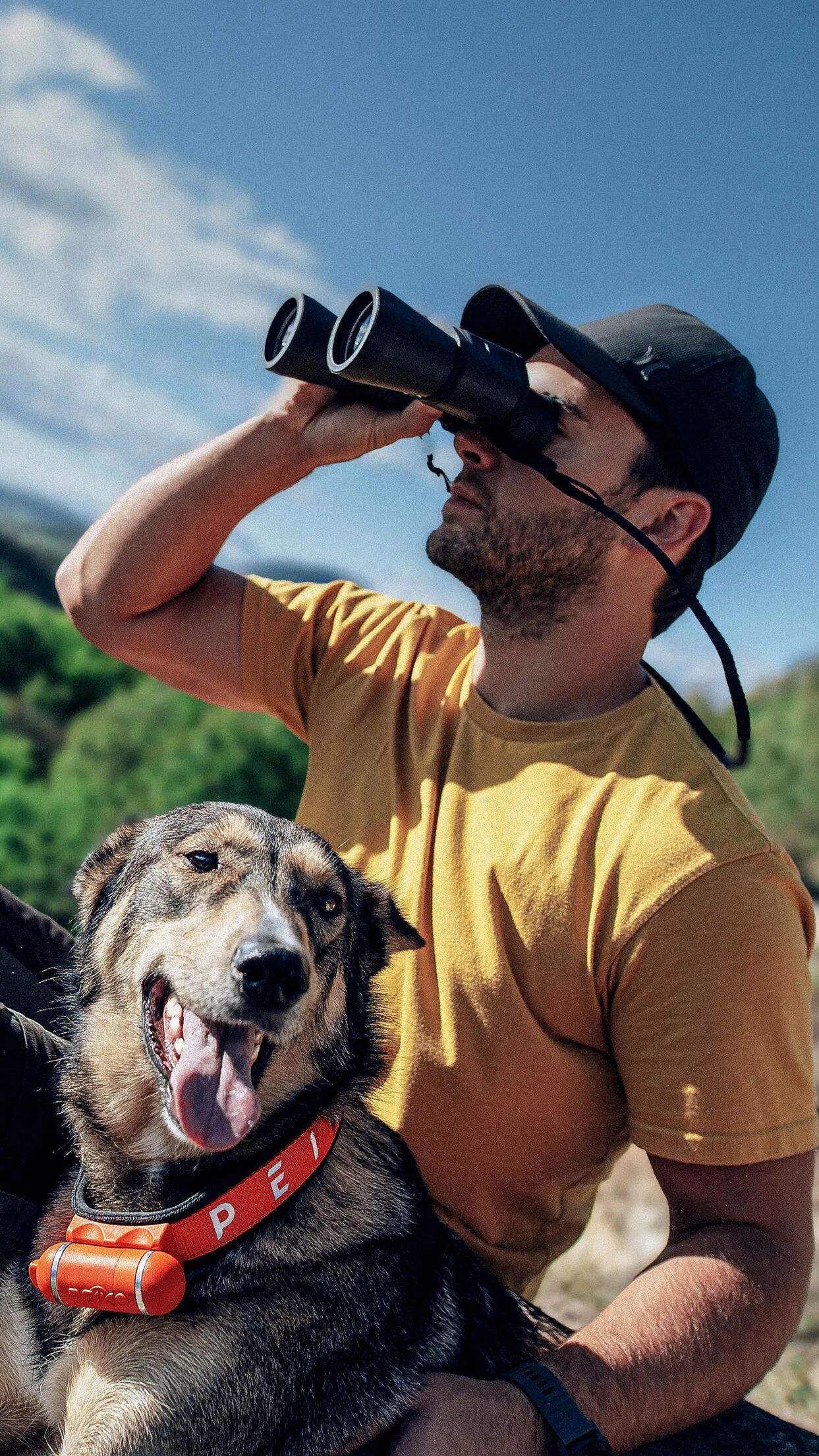 Guy with a huskey wearing an orange PEIKO® QuickLeash™ collar in the mountains